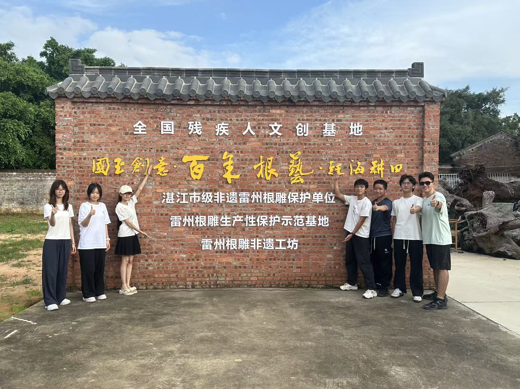 团队在全国残疾人文创基地与雷州根雕非遗工坊标识墙前合影